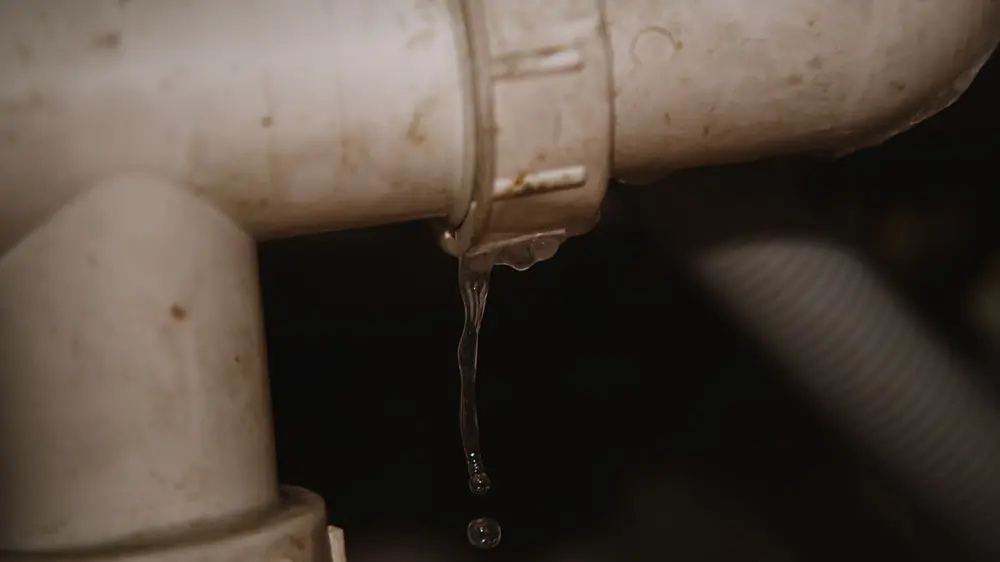 A close up of a plumbing water pipe leaking water.