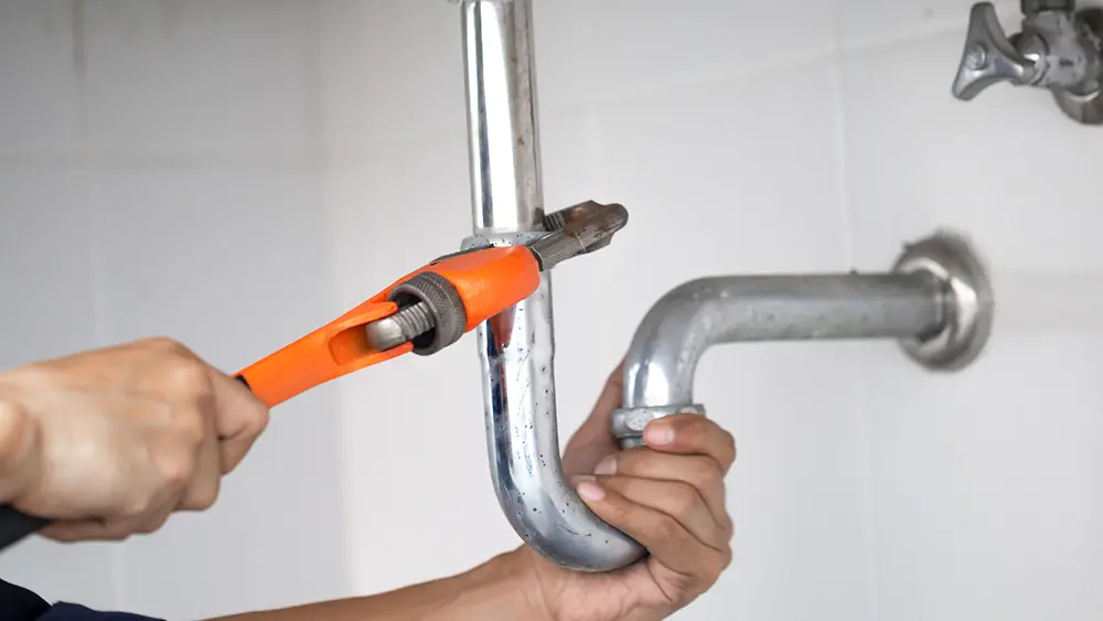 A plumber performing plumbing repairs in a bathroom.