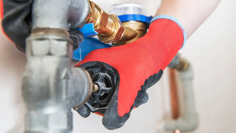 A plumber is performing plumbing work on a water pipe.